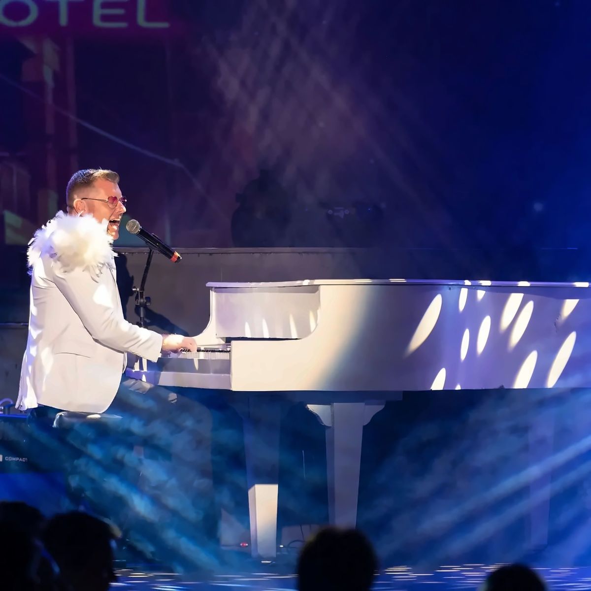 Evan Cullum smiling at the white piano