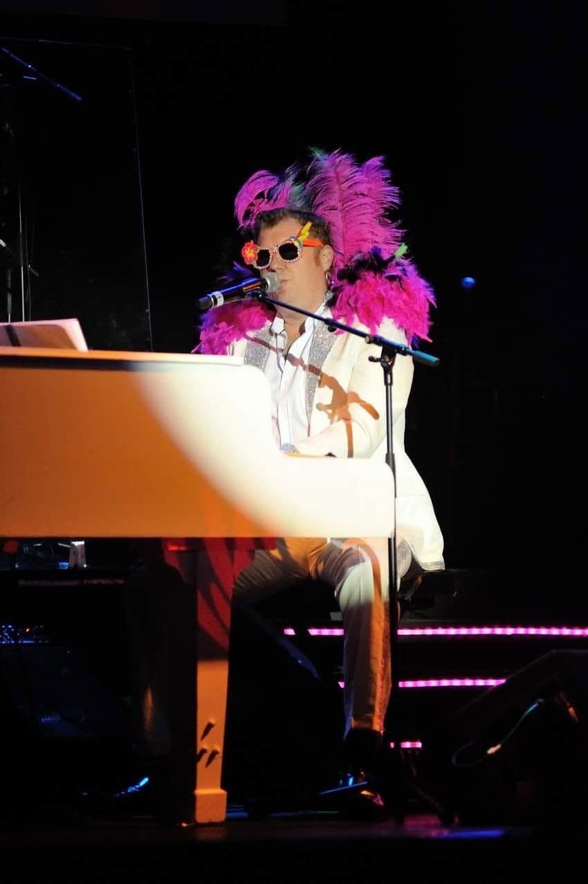 Evan in pink feathers at the piano